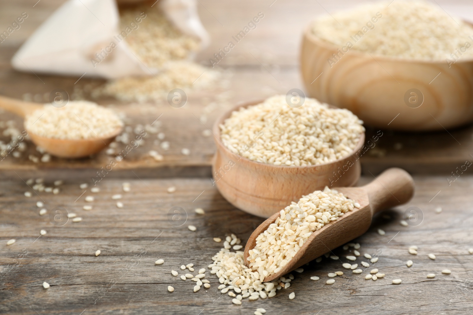 Photo of Bowl and scoop with sesame seeds on wooden table. Space for text