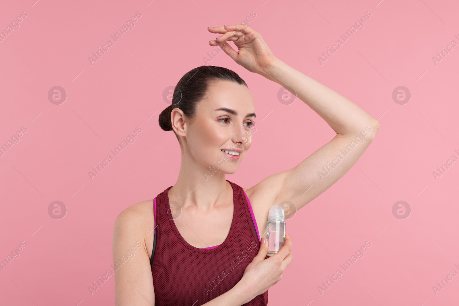 Photo of Beautiful woman applying deodorant on pink background