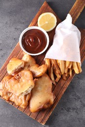 Tasty fish, chips and sauce on grey table, top view