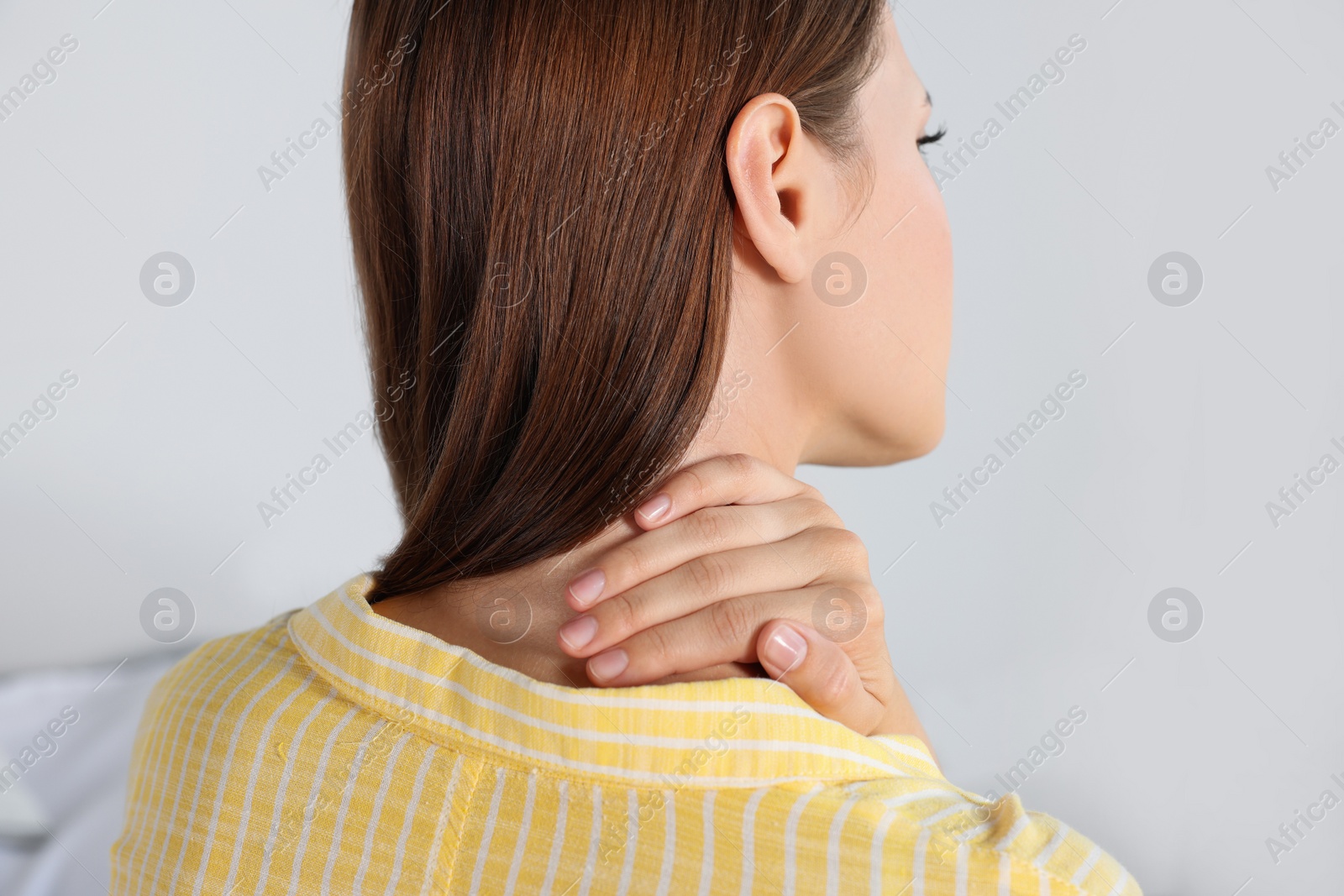 Photo of Woman suffering from neck pain indoors, closeup