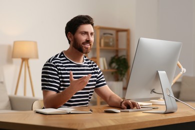 Photo of Home workplace. Happy man having video conference at wooden desk in room