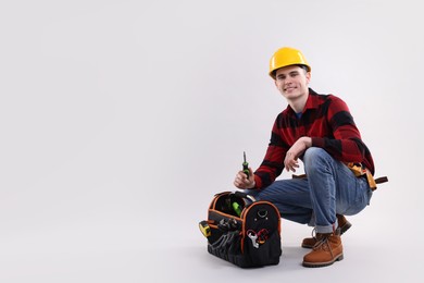 Photo of Professional repairman with tool box on light grey background. Space for text