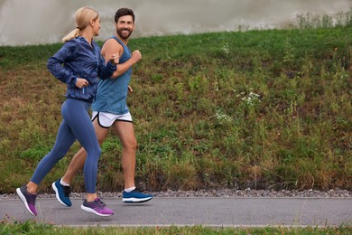 Healthy lifestyle. Happy sporty couple running outdoors, space for text
