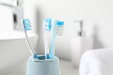 Photo of Plastic toothbrushes in holder on blurred background, closeup. Space for text