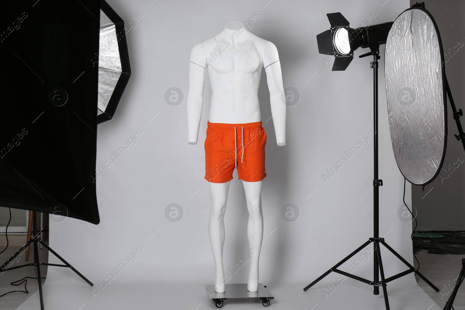 Photo of Stylish clothes on ghost mannequin and professional lighting equipment in modern studio. Fashion photography