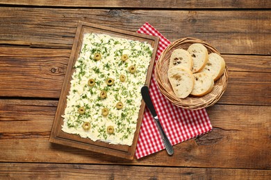 Photo of Fresh butter board with cut olives, bread and knife on wooden table, flat lay