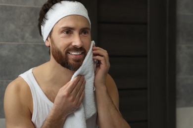 Washing face. Man with headband and towel in bathroom, space for text