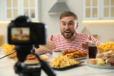 Photo of Food blogger recording eating show on camera in kitchen. Mukbang vlog