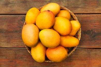 Photo of Delicious ripe juicy mangos on wooden table, top view