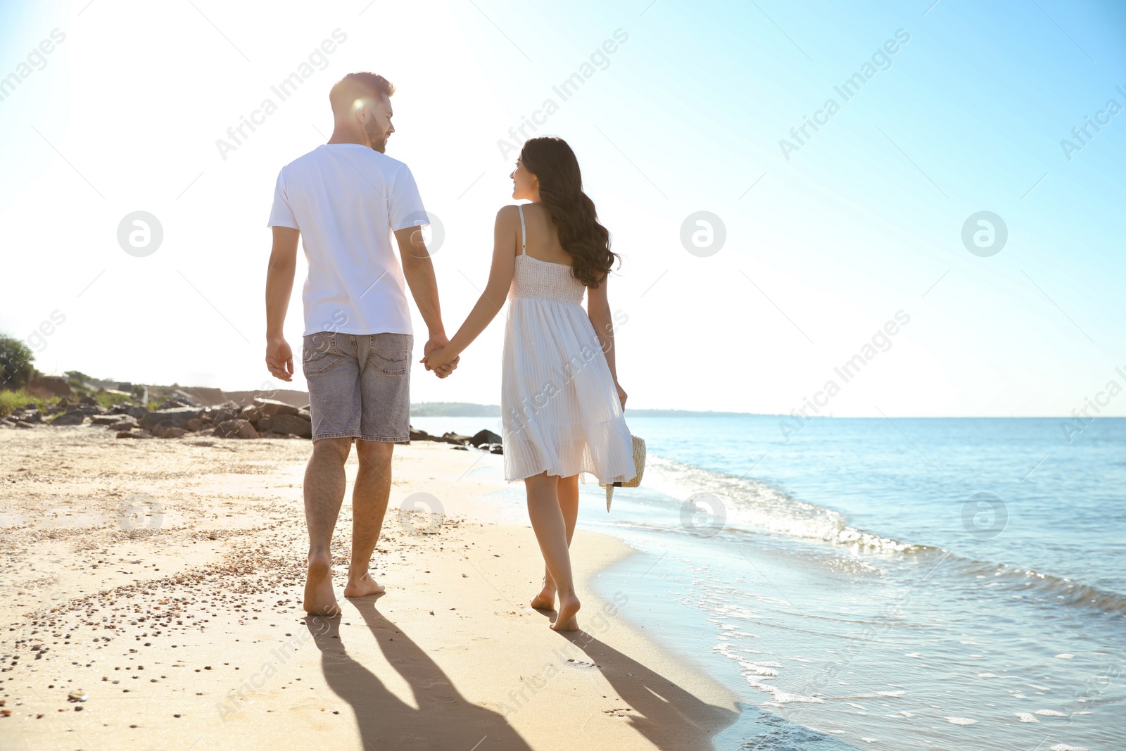 Photo of Happy young couple walking on beach near sea. Honeymoon trip