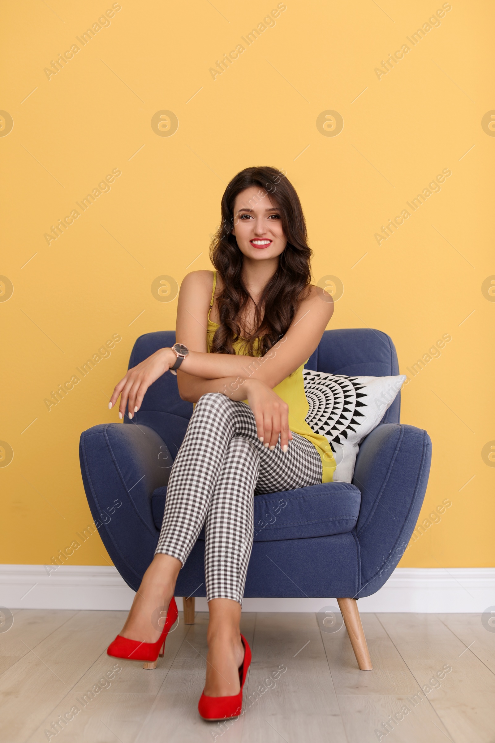 Photo of Beautiful young woman sitting in armchair wearing red elegant shoes