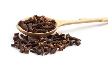 Pile of aromatic dry cloves and wooden spoon on white background, closeup