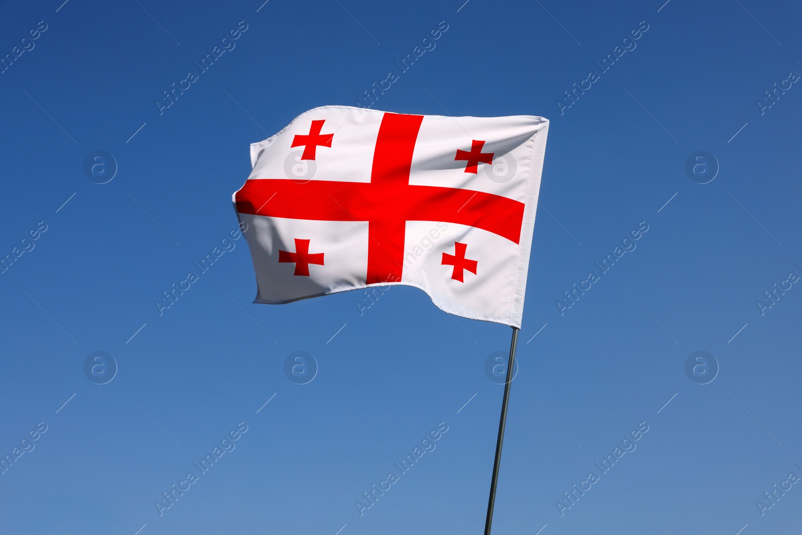 Image of National flag of Georgia against blue sky