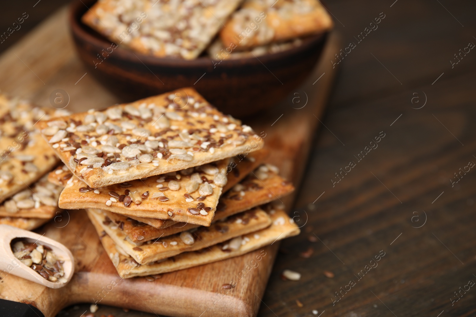 Photo of Cereal crackers with flax, sunflower and sesame seeds on wooden table, closeup. Space for text