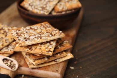 Photo of Cereal crackers with flax, sunflower and sesame seeds on wooden table, closeup. Space for text