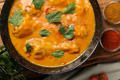 Tasty chicken curry with parsley and ingredients on wooden table, flat lay