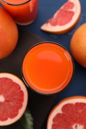 Photo of Tasty grapefruit juice and fresh fruits on blue table, flat lay