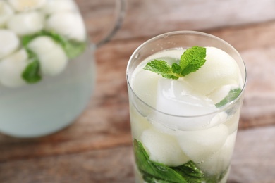 Photo of Glass with tasty melon ball drink on wooden table