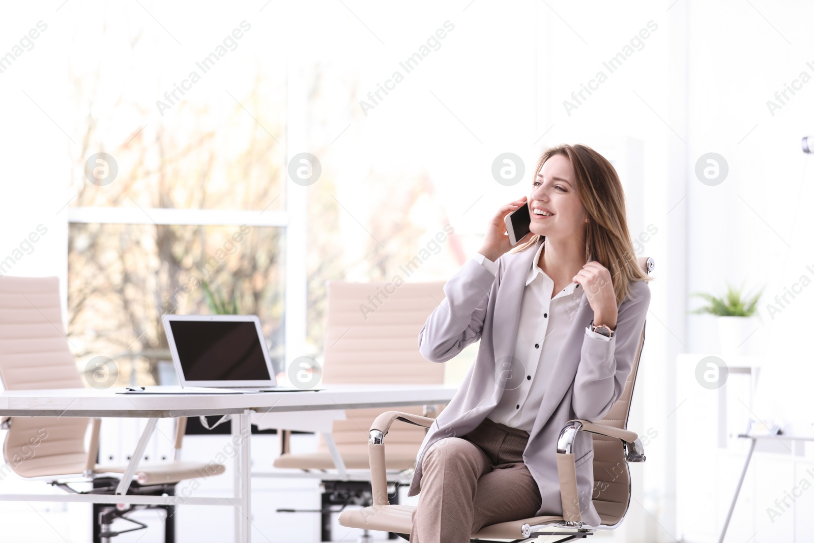 Photo of Young businesswoman with smart phone sitting in office chair at workplace. Space for text