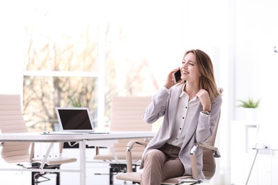 Photo of Young businesswoman with smart phone sitting in office chair at workplace. Space for text