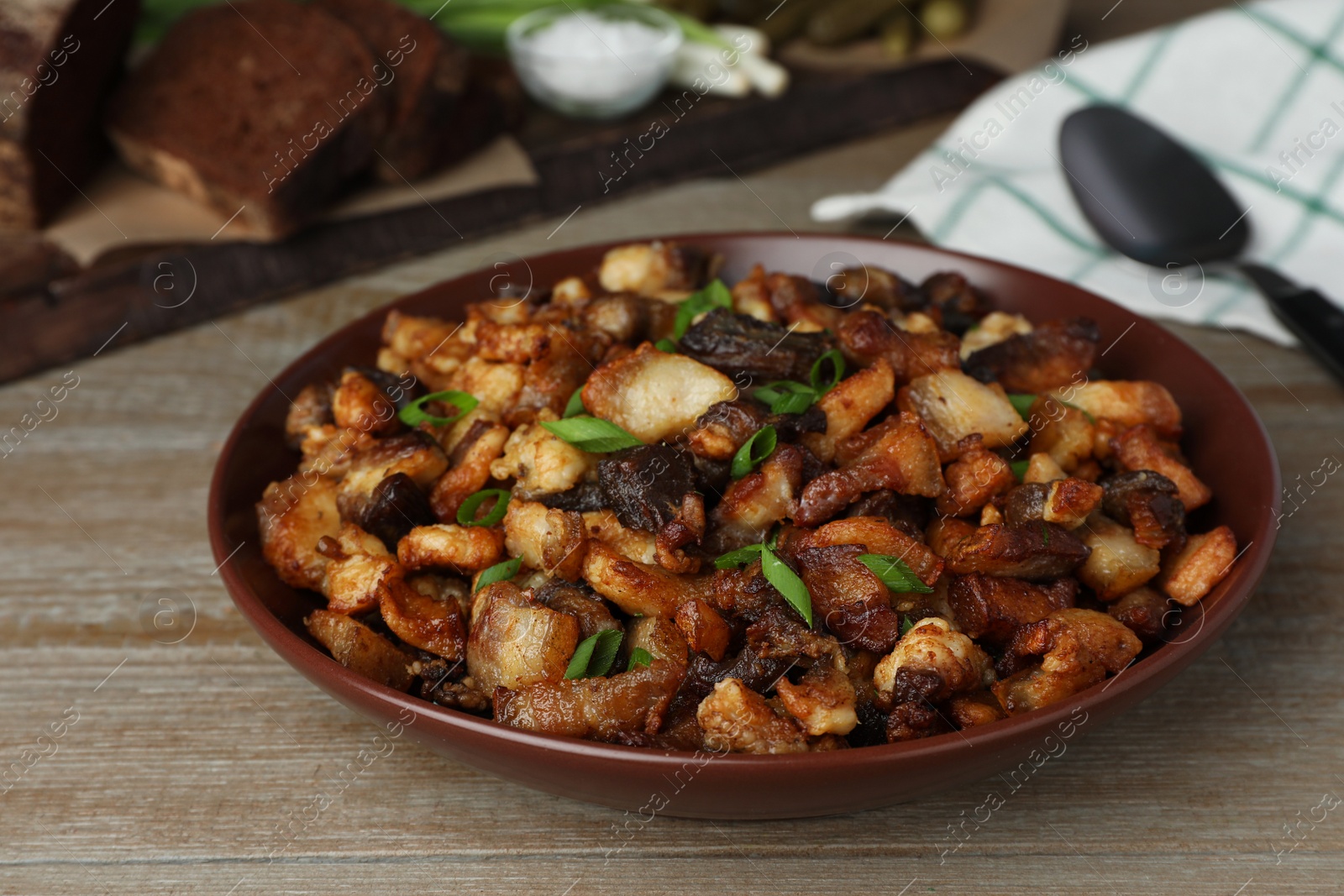 Photo of Tasty fried cracklings on wooden table, closeup. Cooked pork lard