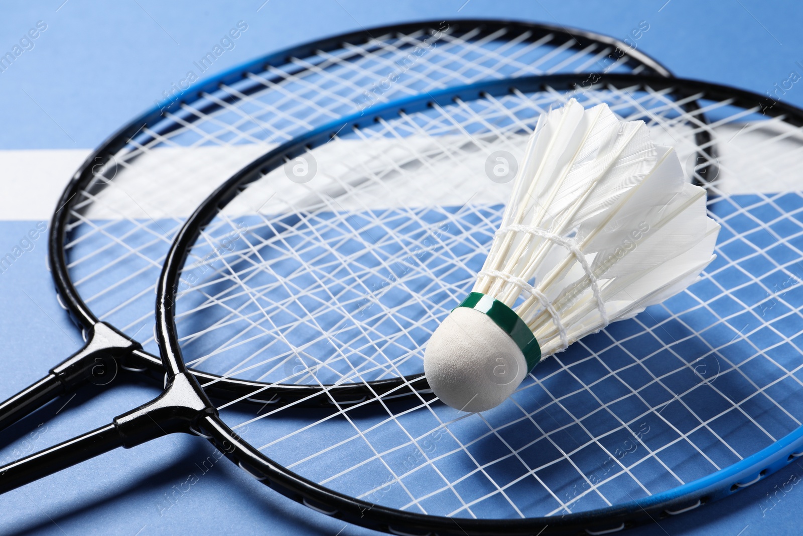 Photo of Feather badminton shuttlecock and rackets on blue background, closeup