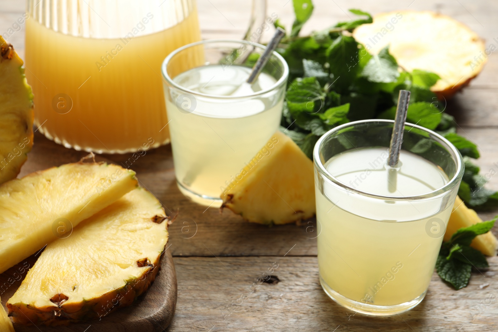 Photo of Delicious pineapple juice and fresh fruit on wooden table