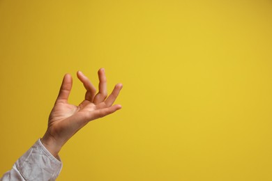 Photo of Woman holding something in hand on yellow background, closeup. Space for text