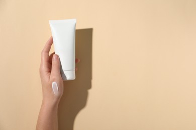 Photo of Woman with tube of hand cream on beige background, top view. Space for text