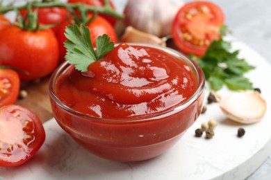 Photo of Delicious ketchup in bowl, parsley and tomatoes on grey table, closeup