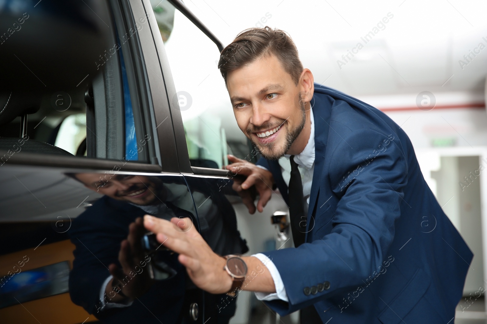 Photo of Handsome man near car in modern auto dealership