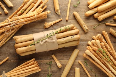 Delicious grissini sticks with thyme on wooden table, flat lay