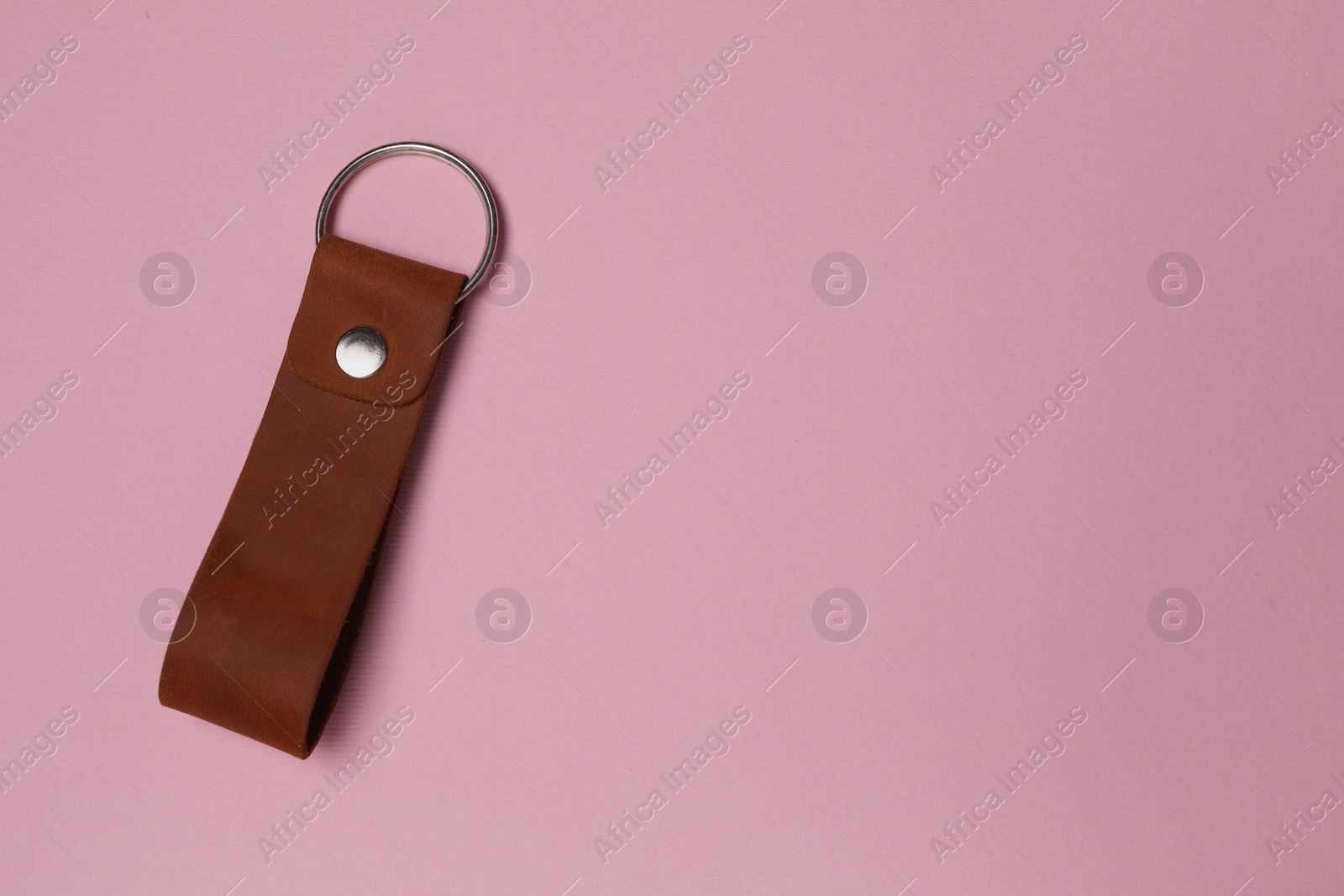 Photo of Leather keychain with Ukrainian coat of arms on pale pink background, top view. Space for text