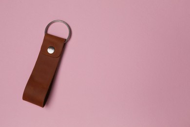 Leather keychain with Ukrainian coat of arms on pale pink background, top view. Space for text