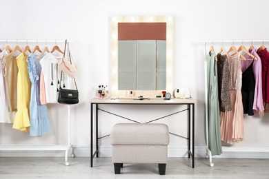 Photo of Stylish room with dressing table, mirror and wardrobe racks