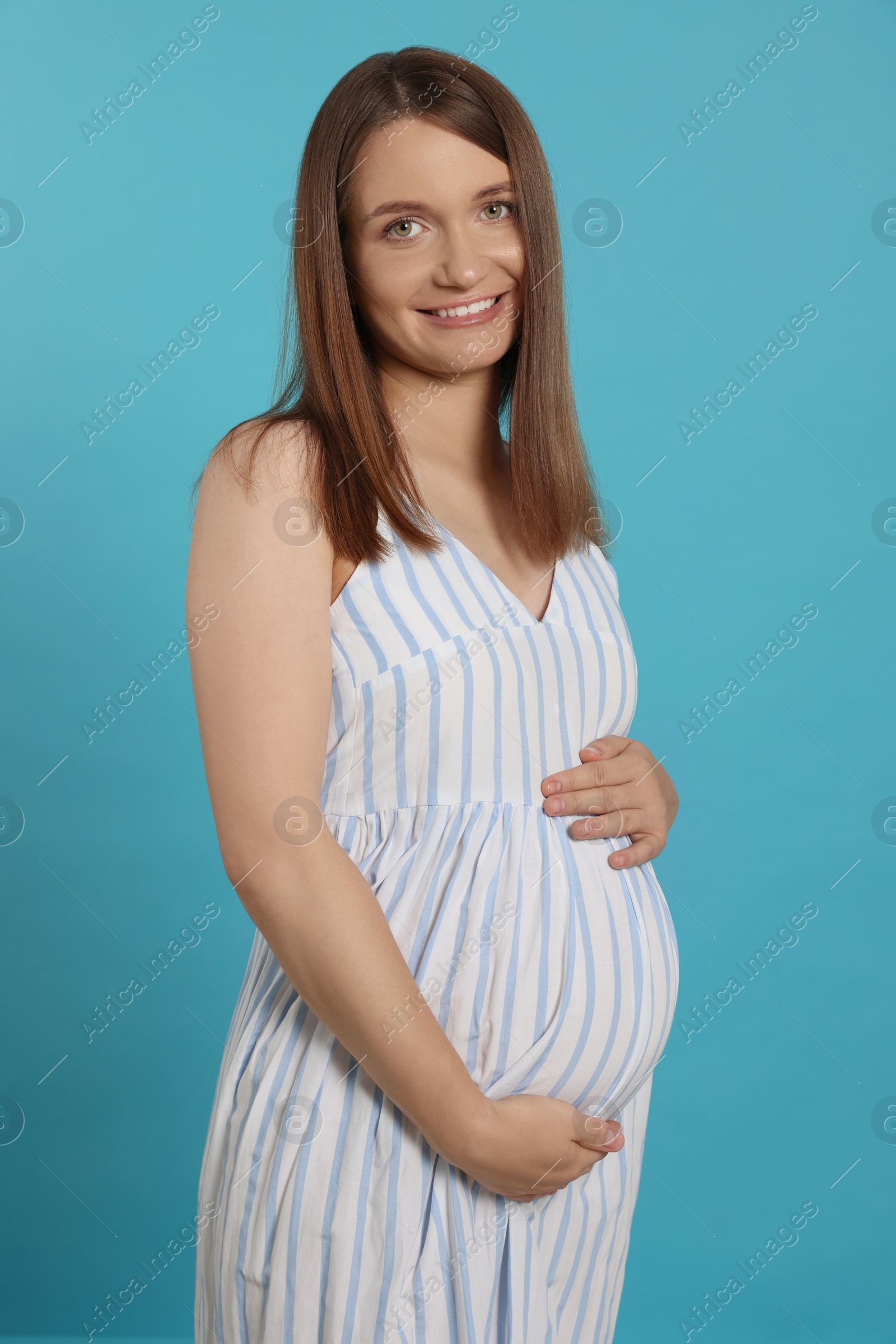 Photo of Happy young pregnant woman on light blue background