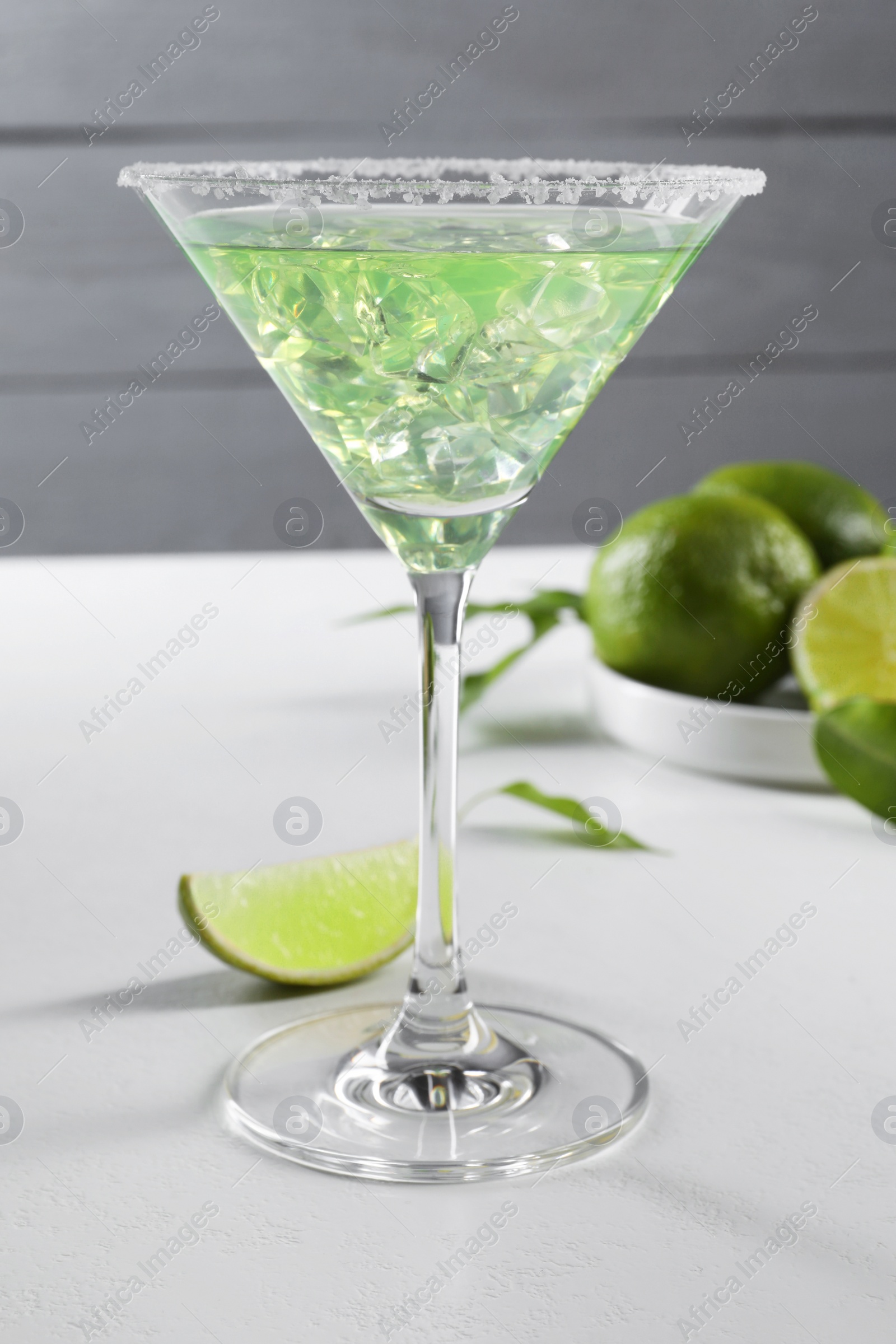 Photo of Delicious Margarita cocktail with ice cubes in glass and lime on white table