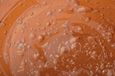 Photo of Pure transparent cosmetic gel on orange background, closeup