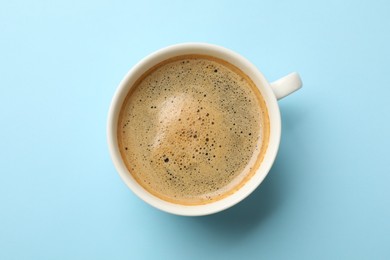 Photo of Aromatic coffee in cup on light blue background, top view