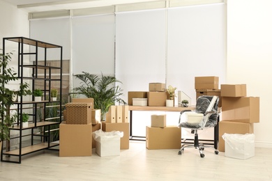 Photo of Cardboard boxes and packed chair in office. Moving day