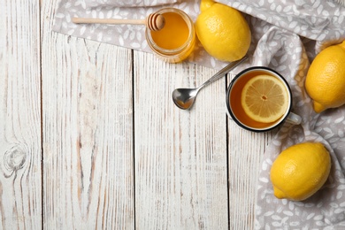 Photo of Cup with hot lemon tea and honey on wooden background, top view. Space for text