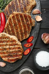 Photo of Delicious grilled pork steaks with spices on wooden table, flat lay