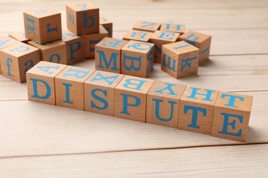Photo of Cubes with word Dispute on light wooden table