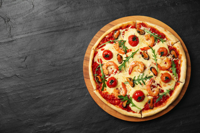 Photo of Delicious seafood pizza on black table, top view. Space for text