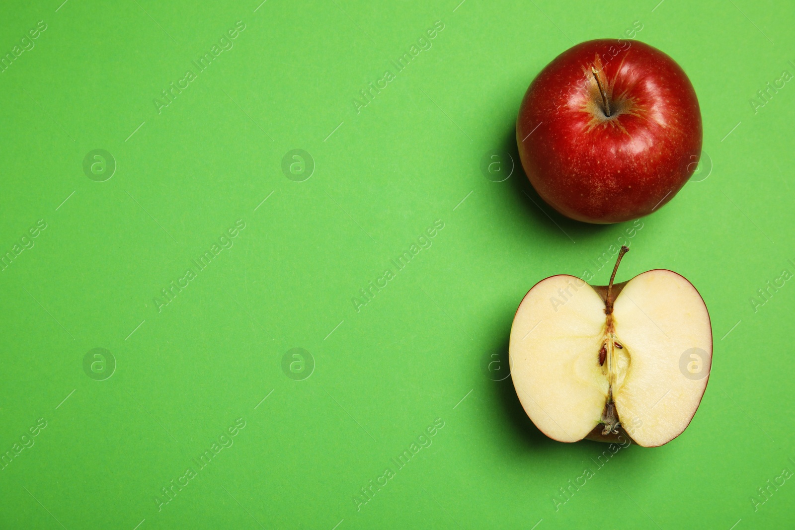 Photo of Flat lay composition with ripe juicy red apples on green background, space for text