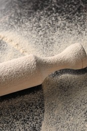 Photo of Scattered flour and rolling pin on table, closeup