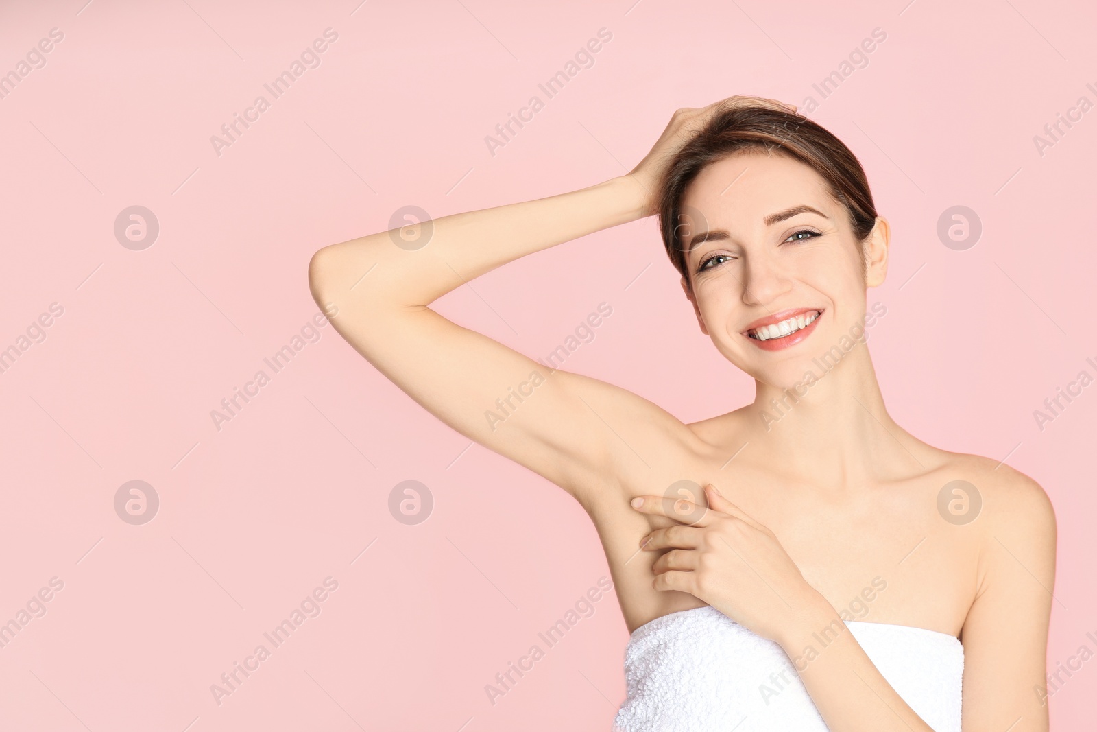 Photo of Young woman showing armpit with smooth clean skin on pink background