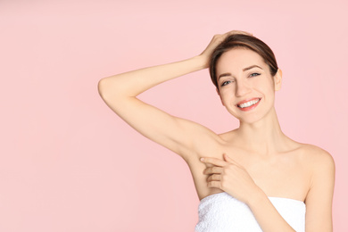 Young woman showing armpit with smooth clean skin on pink background
