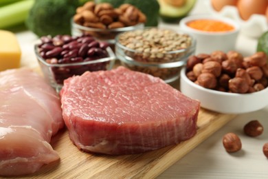 Fresh meat and other products on white wooden table, closeup. Sources of essential amino acids