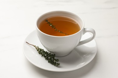 Photo of Cup of aromatic herbal tea with thyme on white table